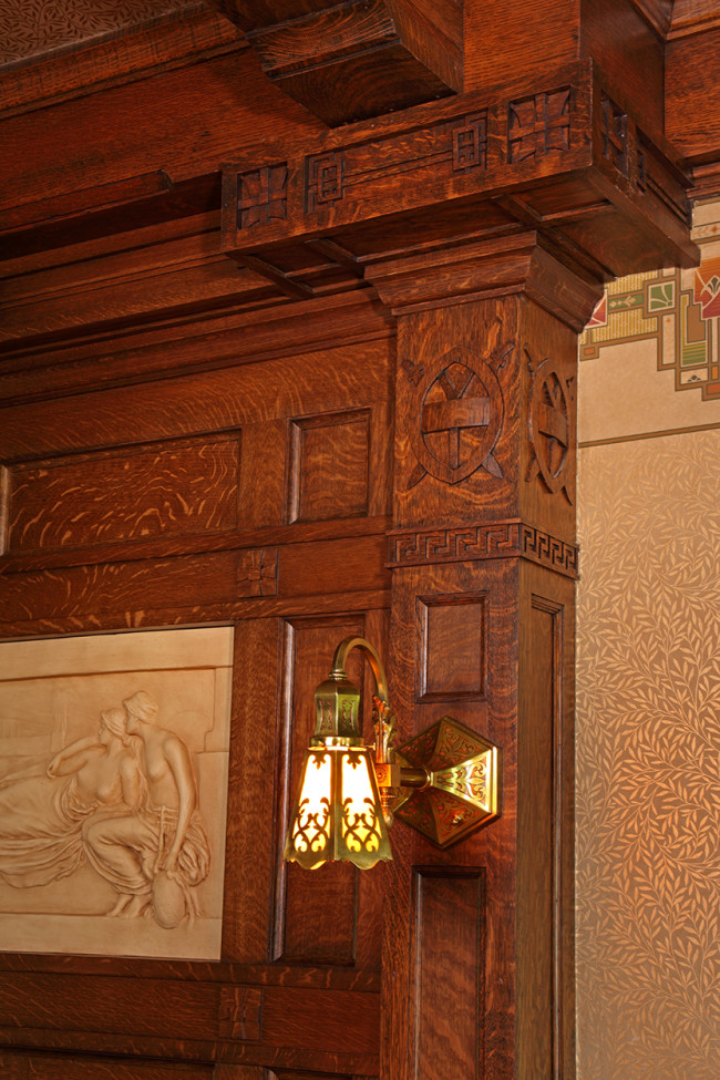 Restored intricately carved but restrained woodwork details on the chimney breast, crown molding, and ceiling beams. Includes a gracefully ornamented glass and brass sconce.