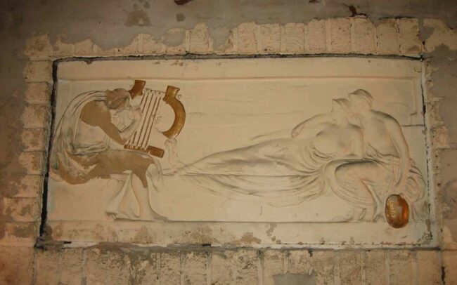 Pre-restoration plaster relief panel that has been deliberately damaged to flatten the image enough to sheetrock over it. Much of the figure of Homer has been removed.