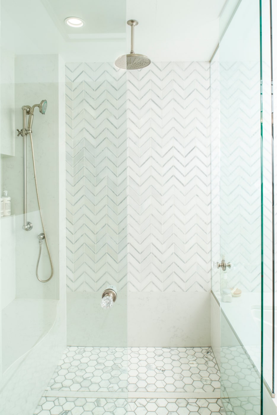 The shower's marble hex-tile floor and herringbone wall are elegant and timeless.