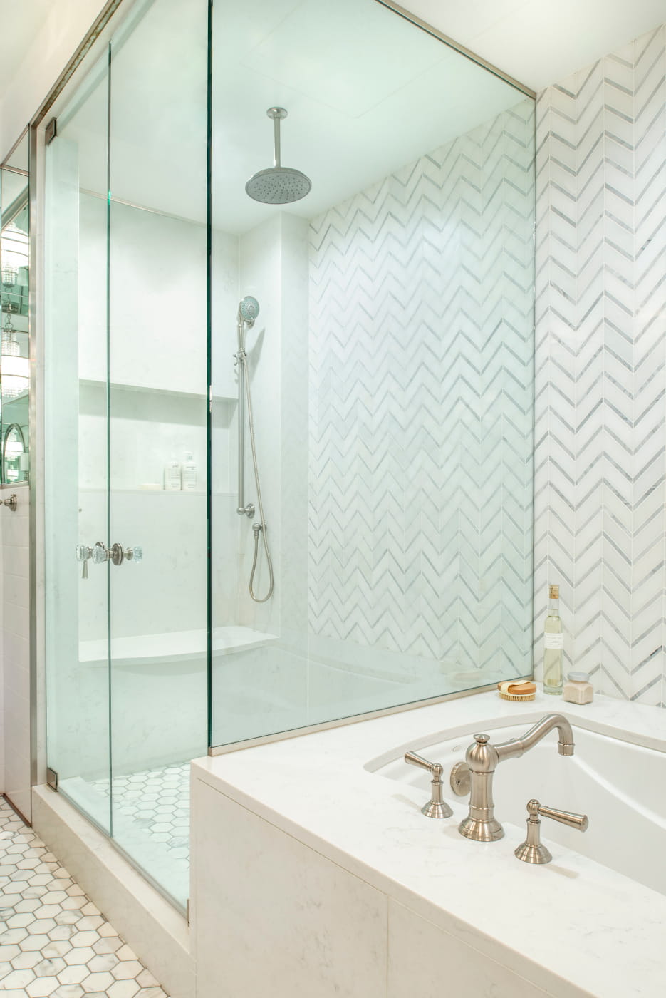The glass shower is generously sized, with a bench seat, a large nook for bottles, and both rain and hand-held shower heads.